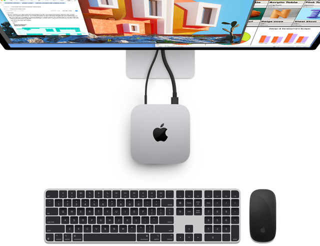 Draufsicht auf das silberne Gehäuse des Mac mini mit Apple Logo. Der Computer ist mit einem Display verbunden, daneben befinden sich die kabellosen Zubehörgeräte Magic Keyboard und Magic Mouse.